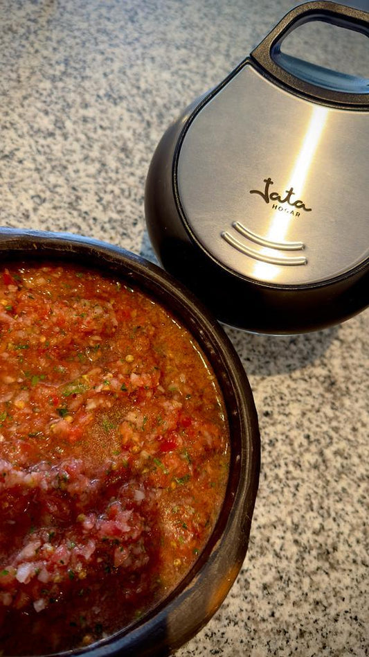 Pebre chileno casero en pocillo de greda junto a electrodoméstico sobre mesón de cocina