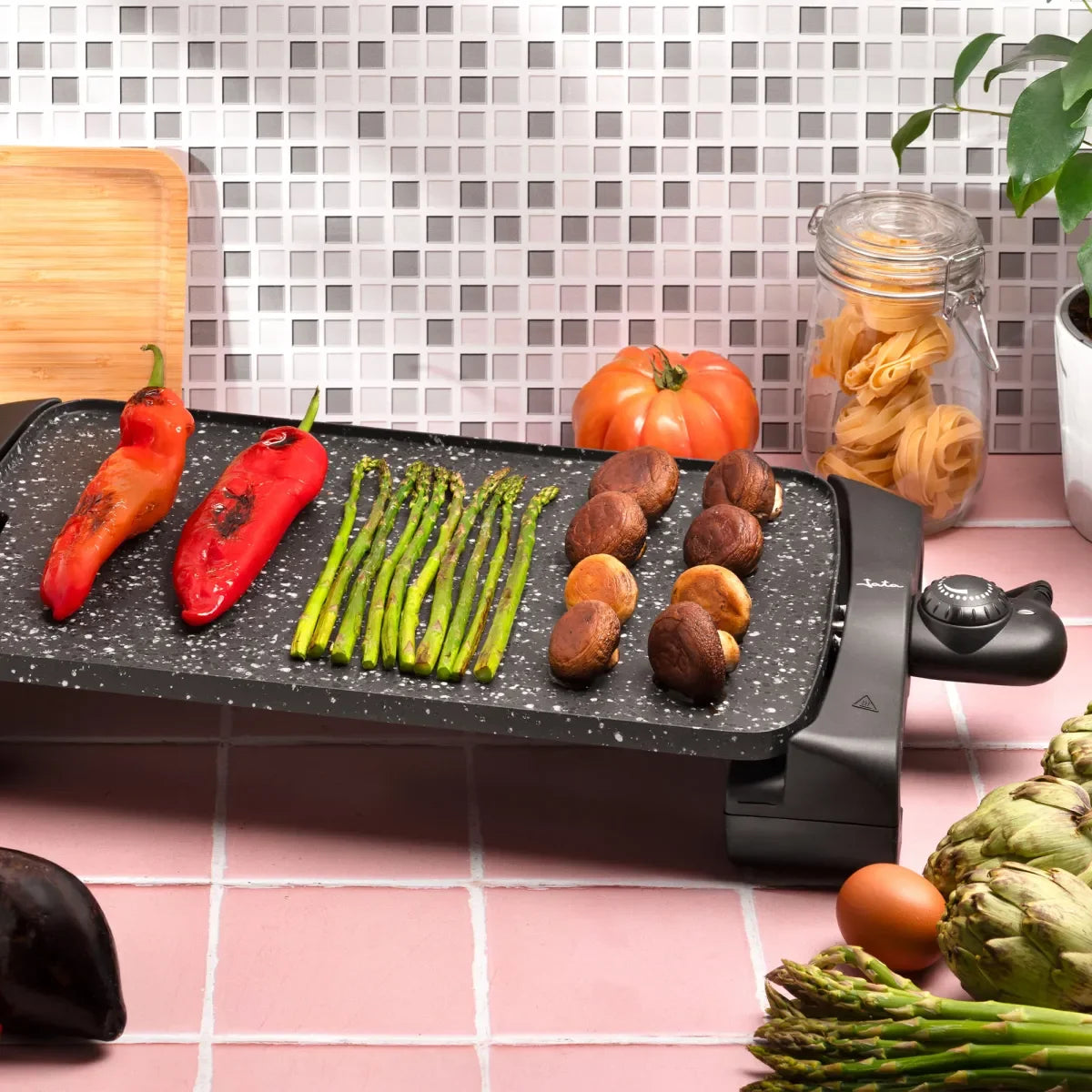 Plancha eléctrica de asar con verduras, pimientos, espárragos y champiñones en cocina moderna