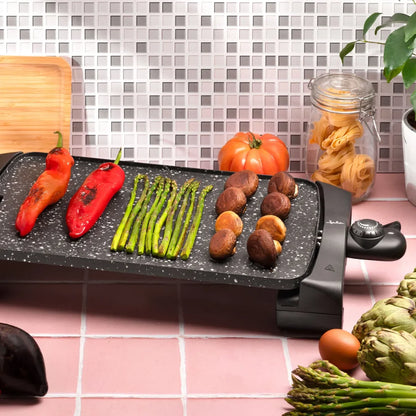 Plancha eléctrica de asar con verduras, pimientos, espárragos y champiñones en cocina moderna